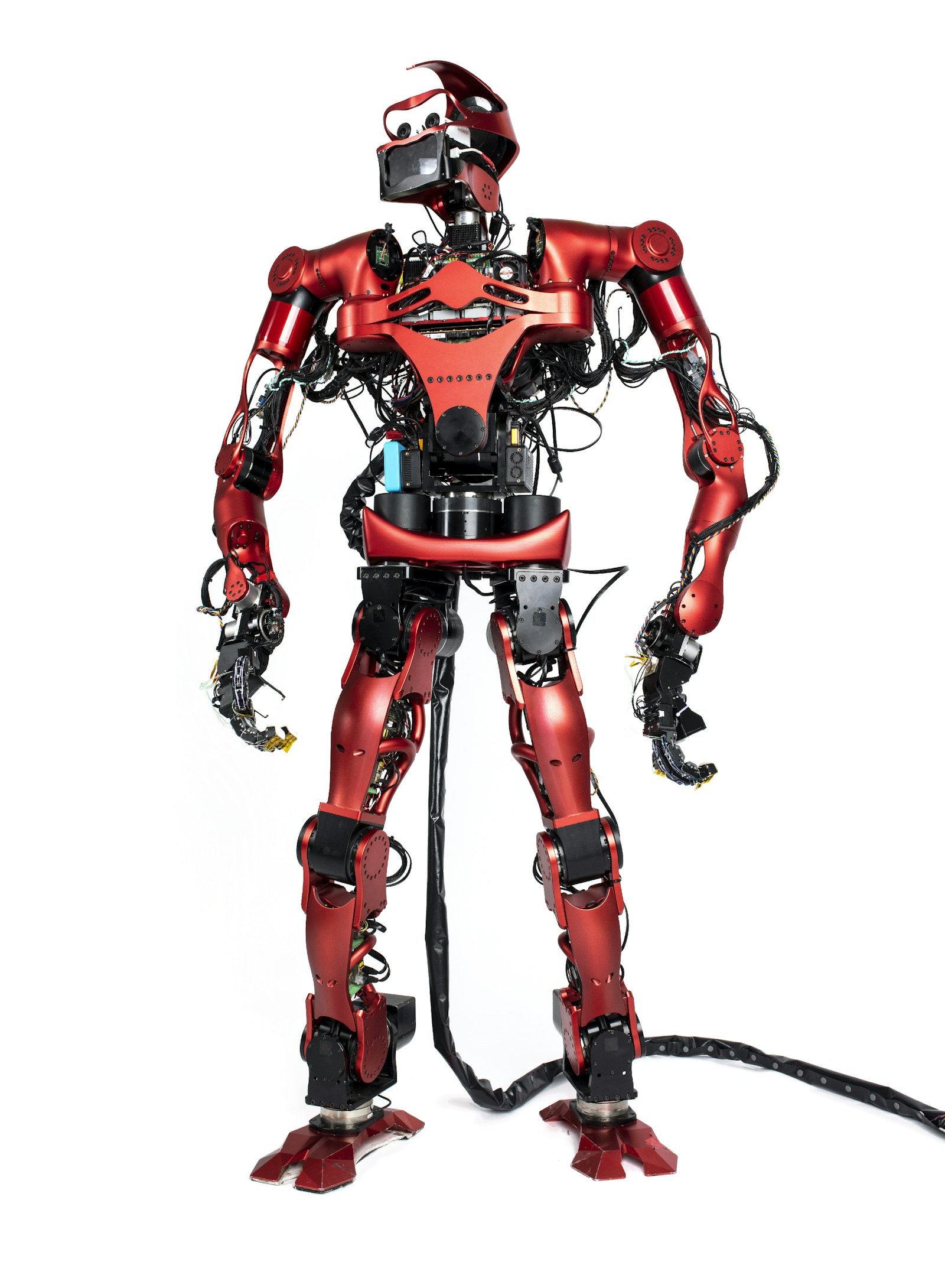 Full-scale red humanoid robot with exposed actuators, wiring, and sensors.